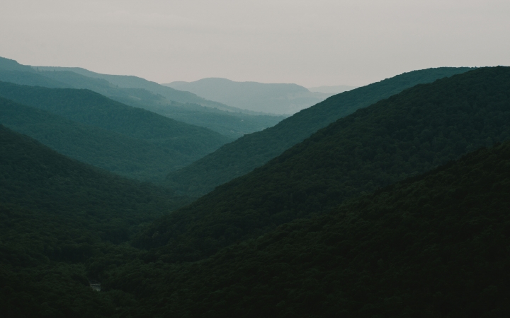 Densely wooded mountains appear in shades of blue under a gray sky